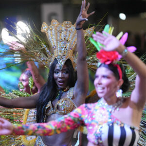 Dos mujeres en un desfile, ambas disfrutando del momento en sus diferentes vestimentas.