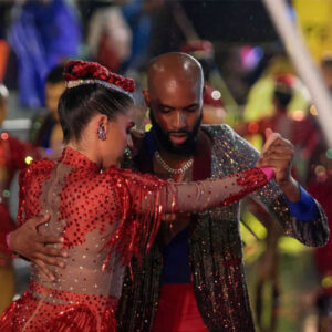 Dos bailarines de salsa vestidos de rojo en un evento nocturno.